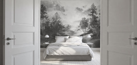 Modern bedroom with white sheets, opened white doors, and a black and white wallpaper mural of a forest landscape. 