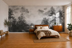 A large-scale black and white forest wallpaper mural displayed on the main wall of a modern bedroom with a wooden bed, matching nightstands, and warm wood flooring.
